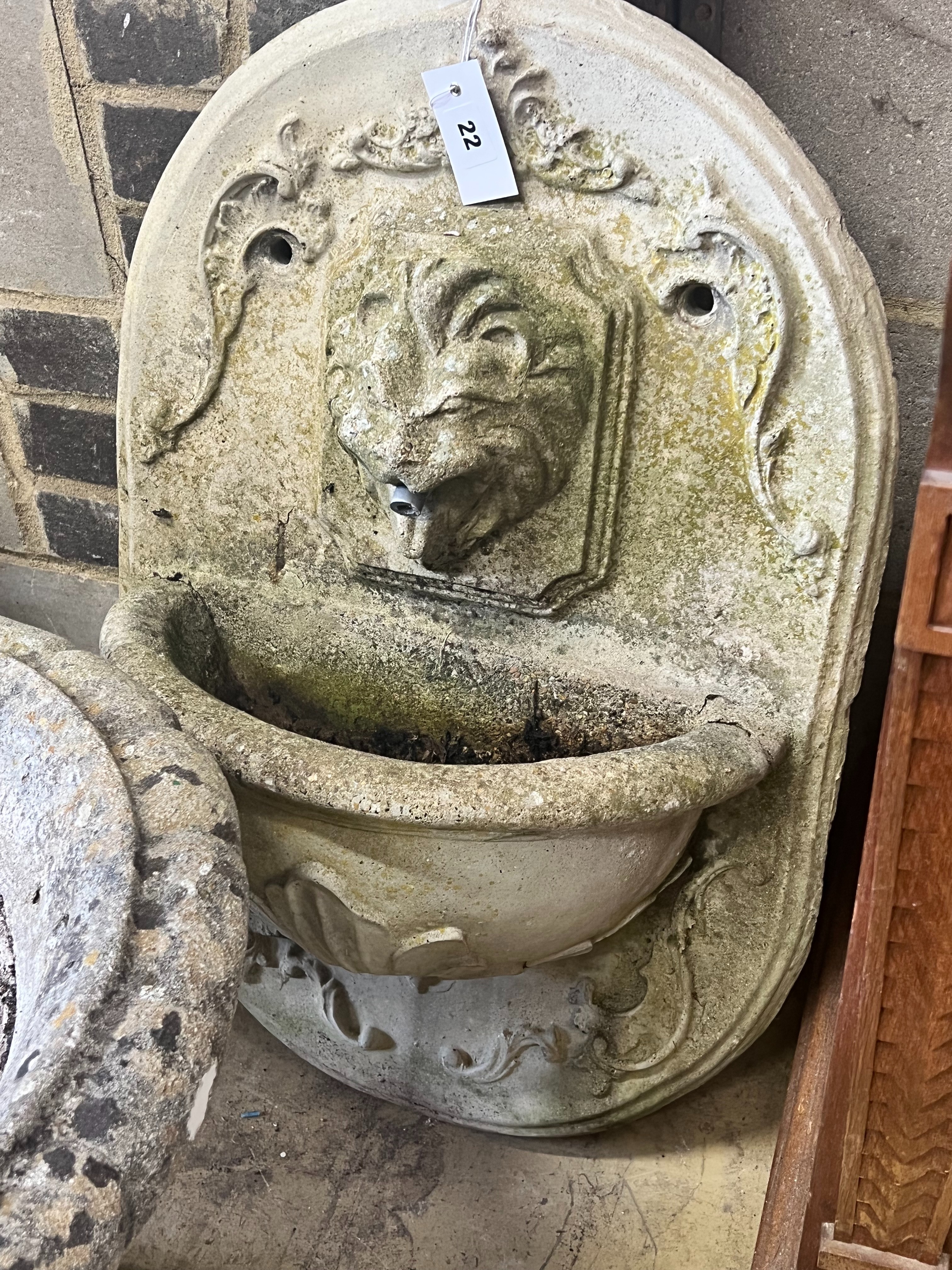 A reconstituted stone garden wall mounted water fountain, with lion mask spout, width 48cm height 70cm